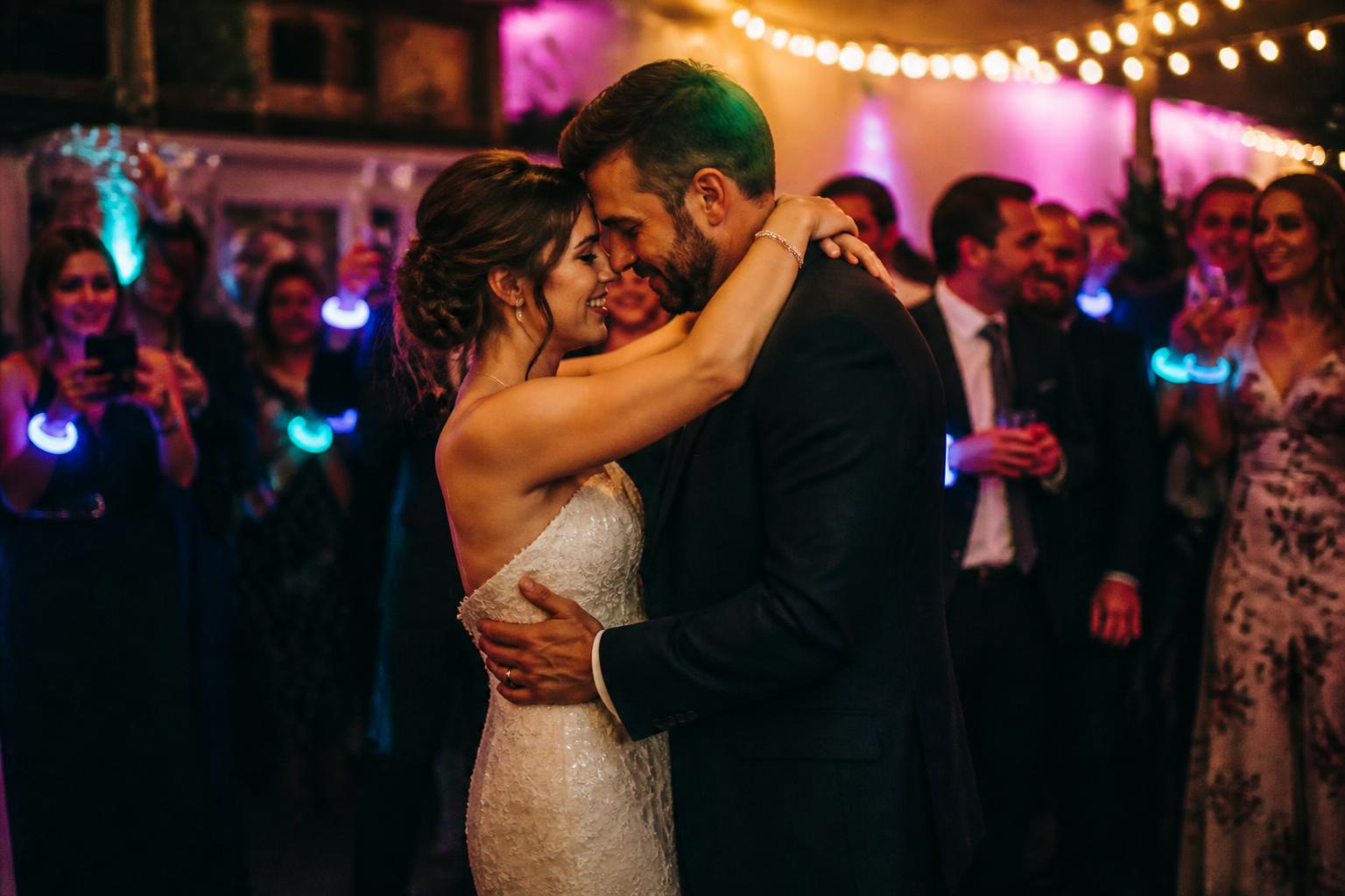 Bride and groom first dance surrounded by guests wearing glowing light wristbands